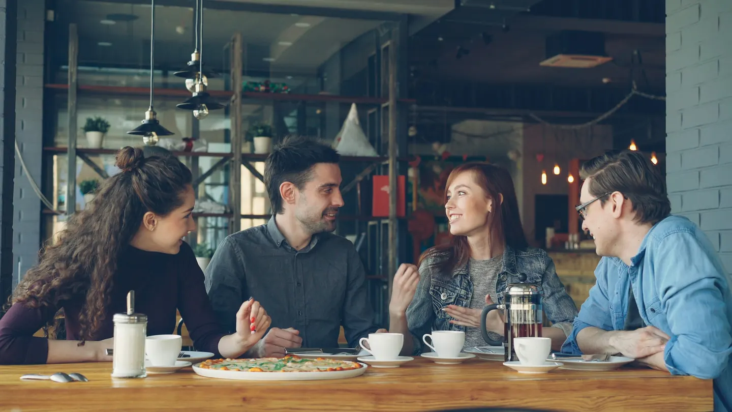 Grupo de amistades conversando y riendo en una cafetería